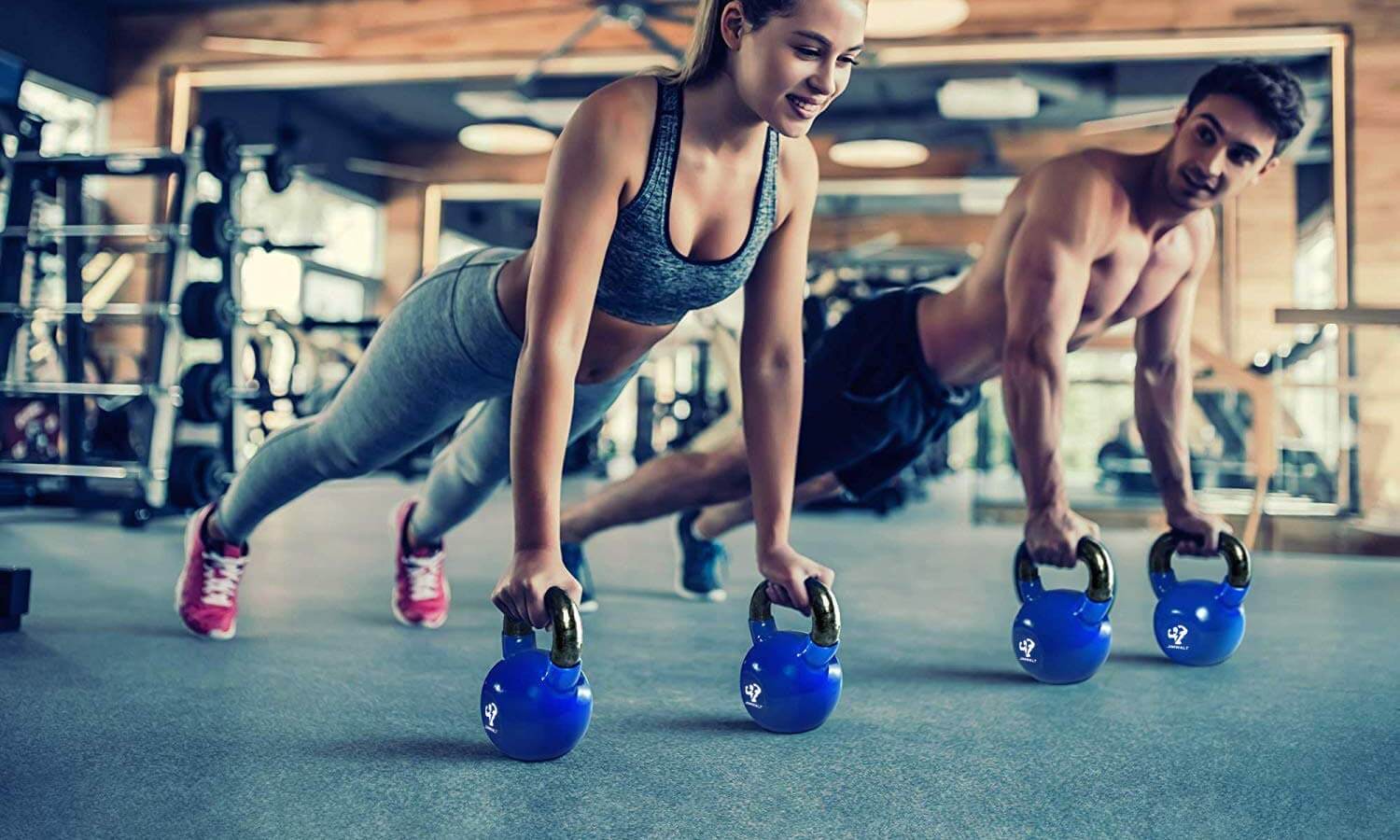 one man and one woman holding blue dumbbells with black handles 