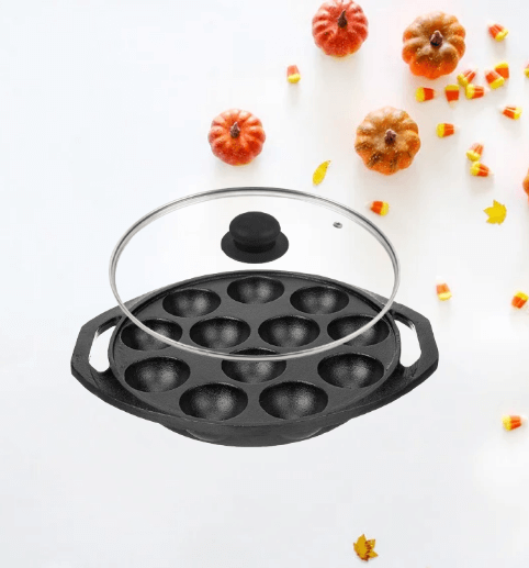 A black cast iron paniyaram pan  round depressions. The pan has two handles and a glass lid 