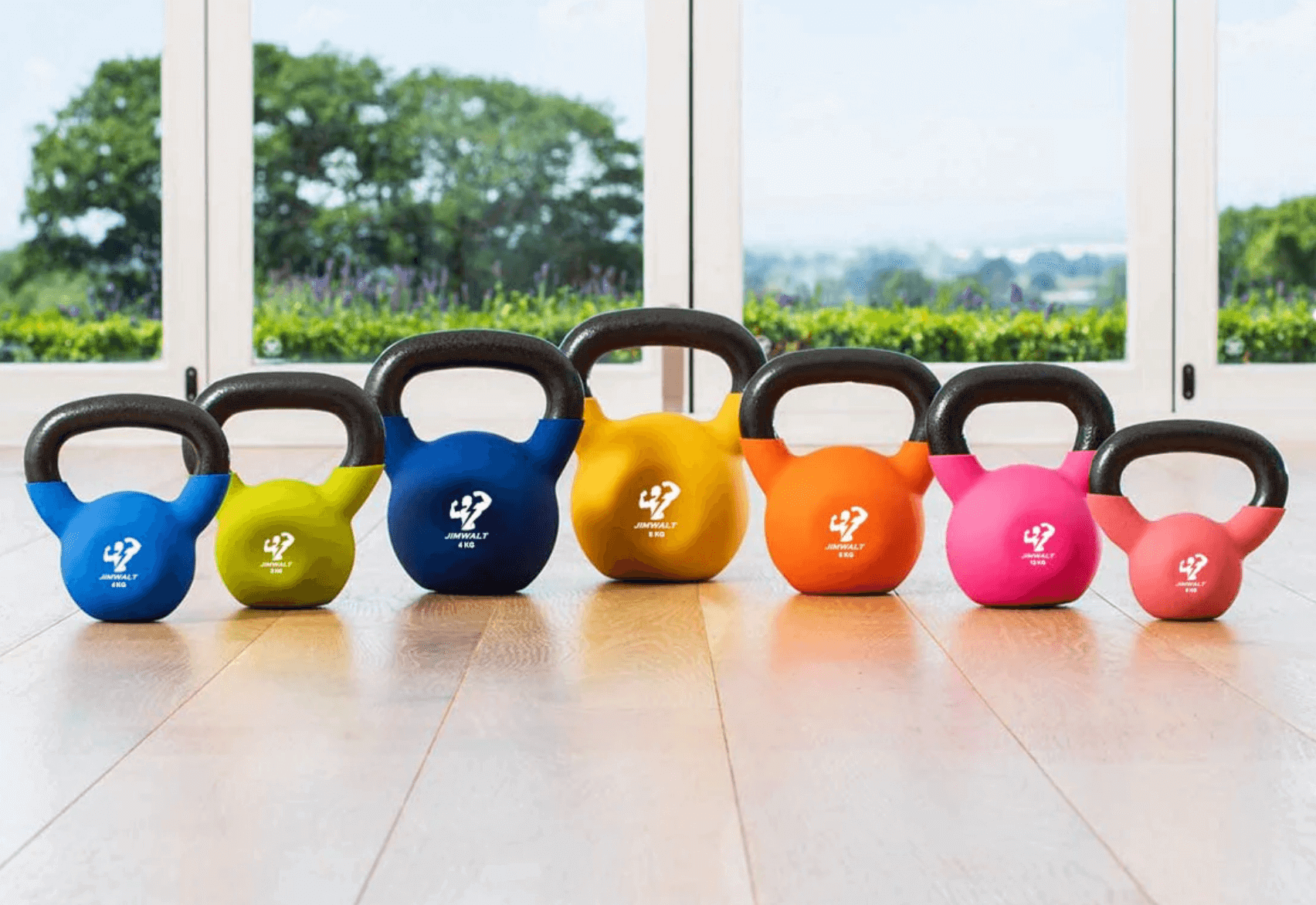 A set of seven kettlebells lined up on a wooden floor.