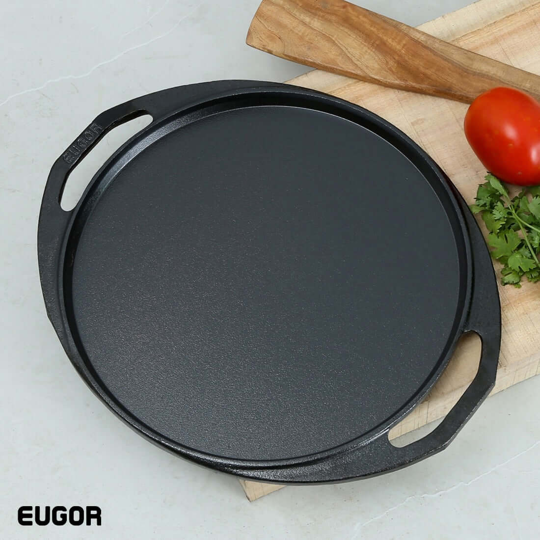 A black cast iron dosa tawa with two handles